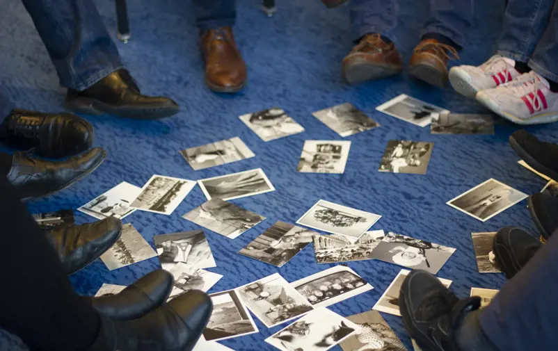 Skor i ring framför vykort utlagda på golvet.