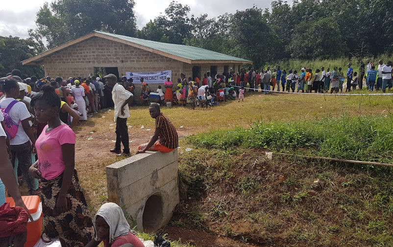 Kvinnor, män och barn köar utanför en vallokal i Liberia.