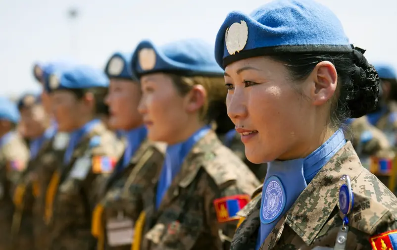 Mongolian UN peacekeeping soldiers standing shoulder to shoulder, photographed slightly from the side.