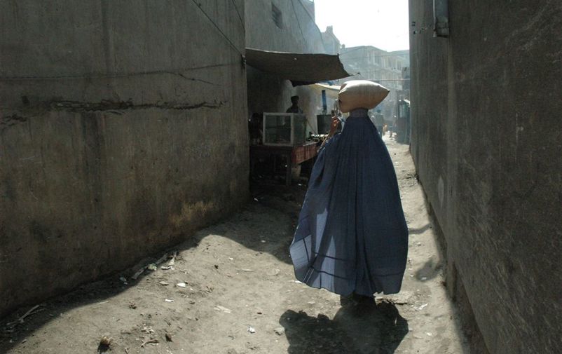En kvinna i burka fotograferad bakifrån på en gata Kabul. 