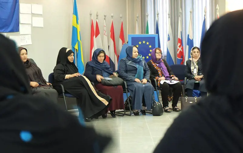 Afghanska kvinnor framför svenska flaggan och EU:s emblem.