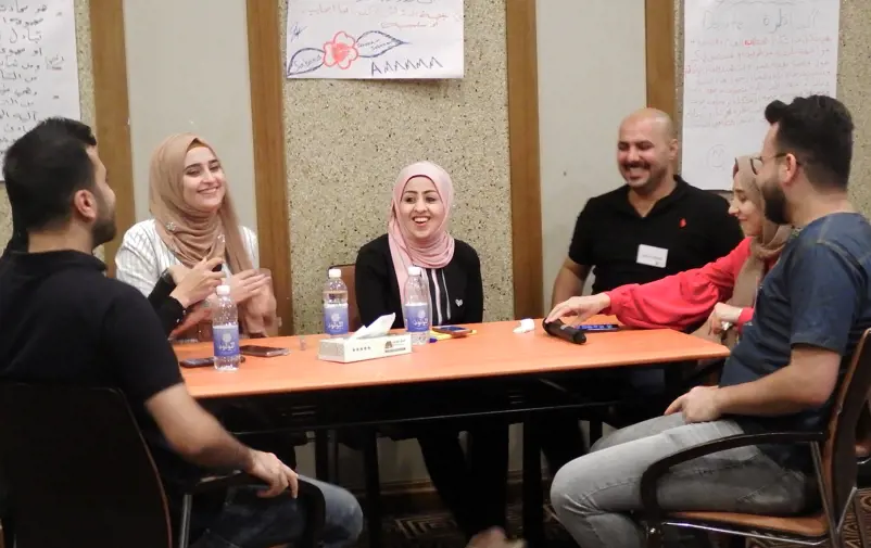 Young Iraqi peacebuilders sitting around a table.