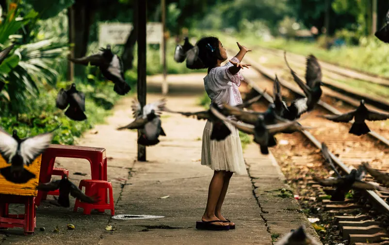 Girl on train station surrounded by flying doves.