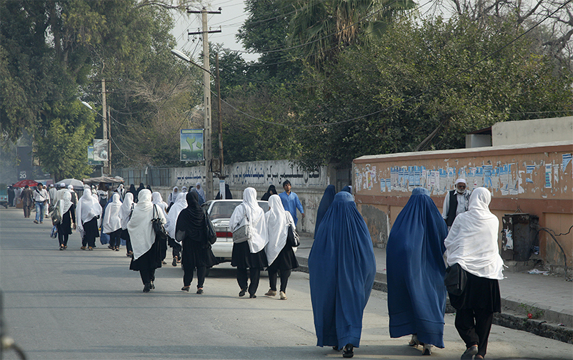 Kvinnor i traditionella kläder promenerar på gata.