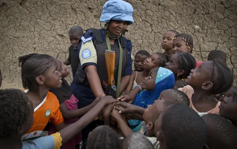 Kvinnlig FN-soldat omringad av barn i Mali.