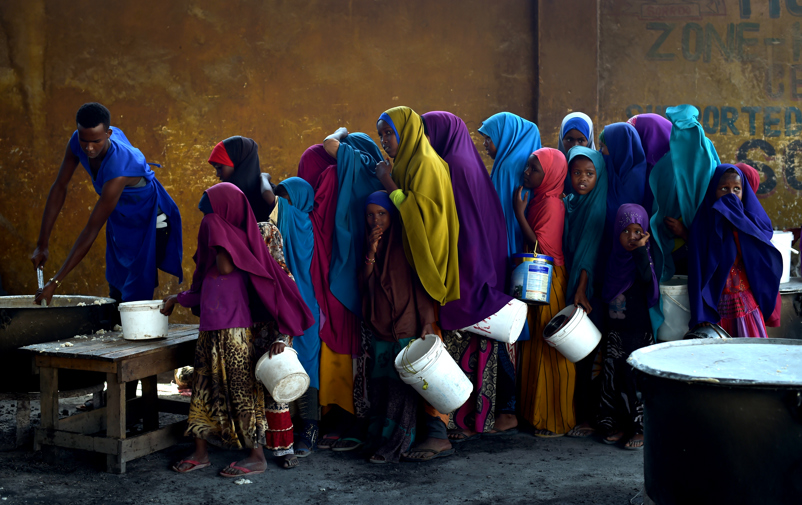 Girls with buckets line up for food.