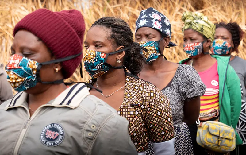 Fem moçambikiska kvinnor i munskydd som står i kö. 