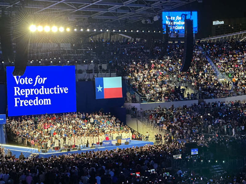 Kampanjmöte på arena. En storbild med texten vote for reproductive freedom.