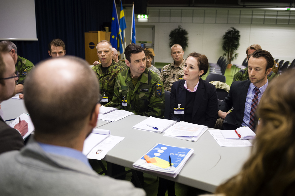 Civilian and military personnel are holding a meeting together.